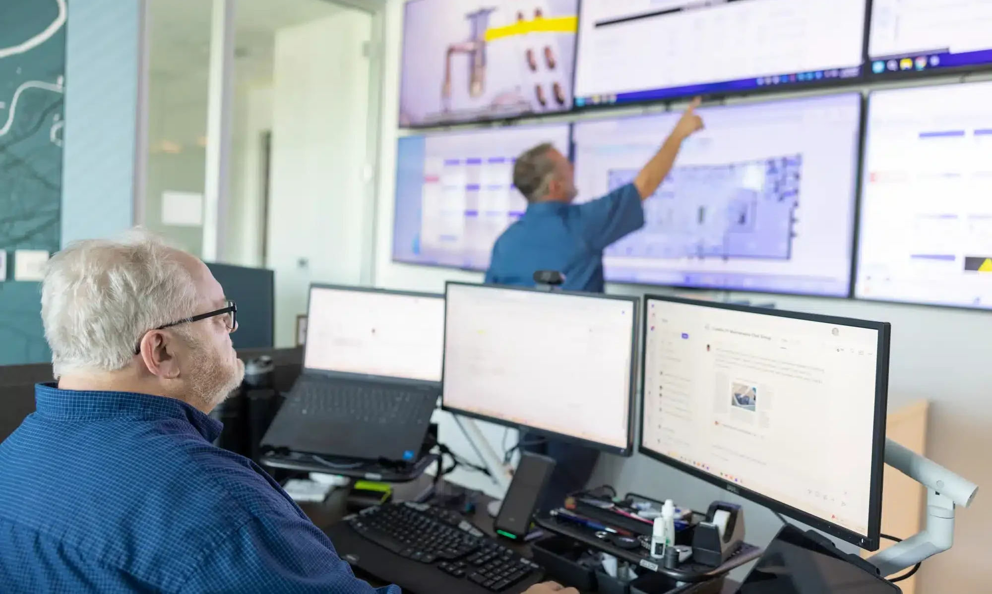 man sitting at desk with 3 monitors in facility needing maintenance